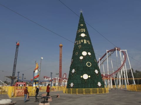 In this Thursday, Dec. 5, 2019 photo, people walk near a large Christmas tree in al-Zawra Park, Baghdad, Iraq. 