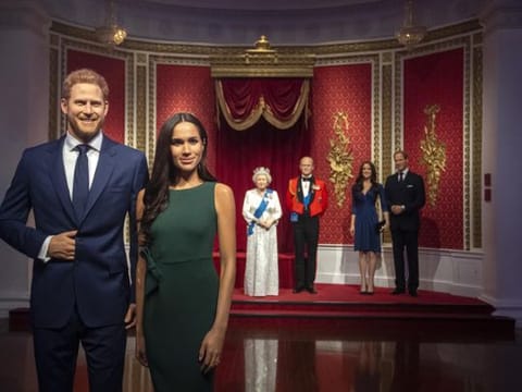 The figures of Britain's Prince Harry and Meghan, Duchess of Sussex, left, are moved from their original positions next to Queen Elizabeth II, Prince Philip and Prince William and Kate, Duchess of Cambridge, at Madame Tussauds in London.