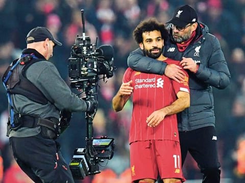 A cameraman films Liverpool manager Jurgen Klopp embracing his team's Egyptian midfielder Mohammed Salah after a crucial win against Manchester United at Anfield on Sunday night.