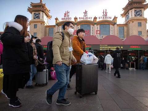 A traveler wears a face mask as he walks outside of the Beijing Railway Station in Beijing 