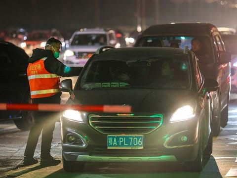 A staff member checks body temperature of a passengers at an exit of a highway in Wuhan, in China's central Hubei province on January 21, 2020. 