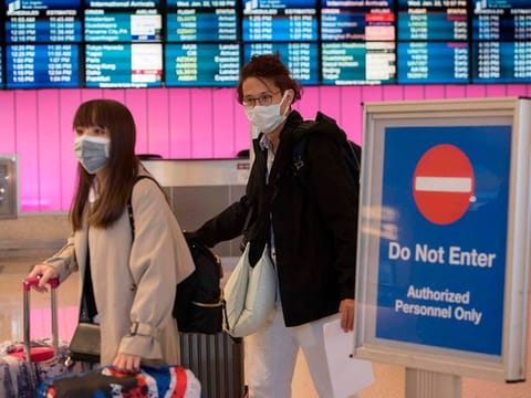 Passengers wear protective masks to protect against the spread of the Coronavirus as they arrive at the Los Angeles International Airport, California, on January 22, 2020. 
