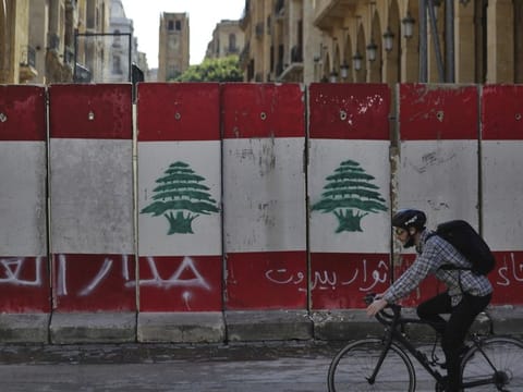 A man rides his bicycle next to a concrete wall installed by authorities to blocks a road leading to the parliament building, in downtown Beirut Friday. Arabic on the wall reads "wall of shame, left, Beirut rebels, centre, Cowards." 