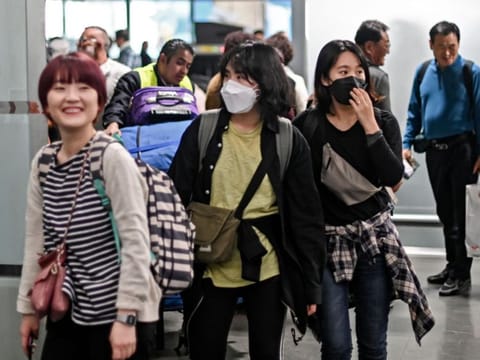 Asian women wear protective masks against the spread of coronavirus as they arrive at the Mexico City International Airport, on January 29, 2020. 
