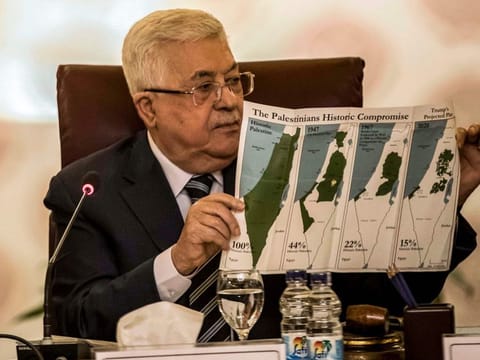 Palestinian president Mahmoud Abbas holds a placard showing maps of (left to right) historical Palestine, the 1947 United Nations partition plan on Palestine, the 1948-1967 borders between the Palestinian territories and Israel, and a current map of the Palestinian territories without Israeli-annexed areas and colonies, as he attends an Arab League emergency meeting discussing the US-brokered proposal for a settlement of the Middle East conflict at the league headquarters in Cairo on February 1.
