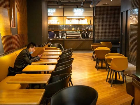 A man wearing a face mask waits for his food at an empty restaurant in Beijing. 