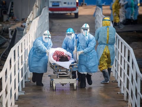 Medical workers in protective suits help transfer a group of patients into the newly-completed Huoshenshan temporary field hospital in Wuhan in central China's Hubei province. 