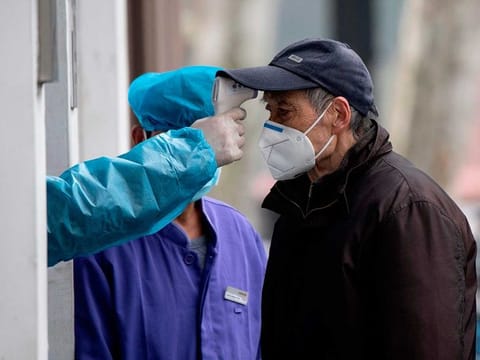 An elderly man wearing a face mask has his temperature checked before entering a community hospital in Shanghai on February 13, 2020. This picture has been  used for illustrative purposes only.