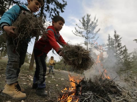 Internally displaced children start a fire at a makeshift camp in Qatmah village, West of Azaz, Syria.