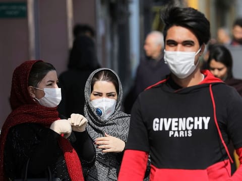 Pedestrians wear masks to help guard against the Coronavirus, in downtown Tehran. 