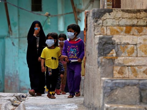Iraqi children wear protective masks as they walk near a religious school where the first coronavirus case was detected, following the outbreak of the new coronavirus, in the holy city of Najaf