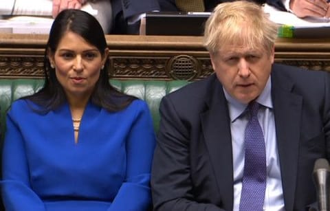 A video grab from footage broadcast by the UK Parliament's Parliamentary Recording Unit (PRU) shows Britain's Prime Minister Boris Johnson (R) and Britain's Home Secretary Priti Patel react during Prime Minister's Question time (PMQs) in the House of Commons in London 