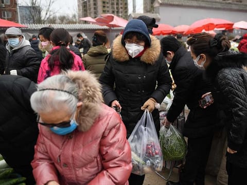 Local residents wear masks as a preventive measure against the COVID-19 coronavirus as they shop for fruit and vegetables in a busy market in Beijing on February 27, 2020. 