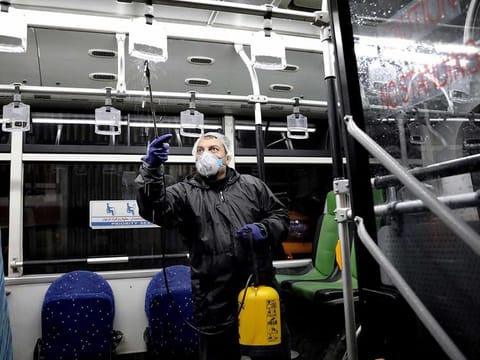 A worker disinfects a public bus against coronavirus in Tehran, Iran, in early morning of Wednesday, Feb. 26, 2020.