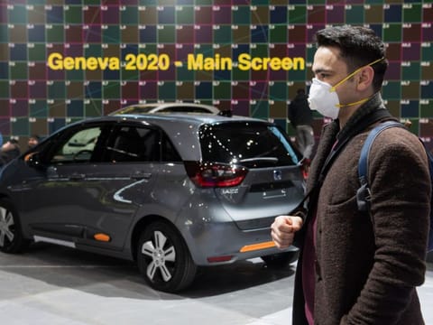 AFP 
A man wearing a mask stand near a car on Friday at the Geneva International Motor Show which has been cancelled due to the Covid-19 epidemic. The Geneva International Motor Show, a major event on the auto industry calendar, has been cancelled after Switzerland banned large gatherings amid the new coronavirus epidemic, local authorities said.
