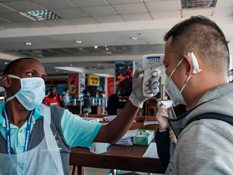 A passenger originating from China has his body temparature taken upon arrival on an international flight as he waits to be screened for signs of the novel coronavirus at Entebbe Airport on March 3, 2020. 