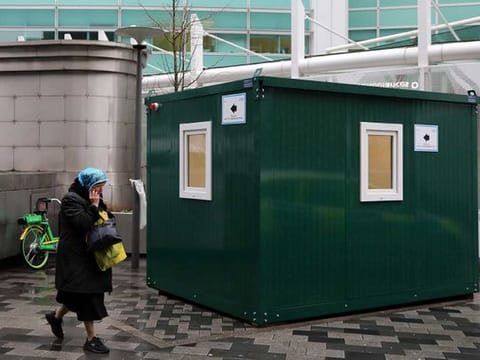 A pedestrian walks past an NHS 111 Coronavirus Pod, for people who believe they may be suffering from the virus, to attend and speak to doctors outside University College Hospital in London on March 5. 
