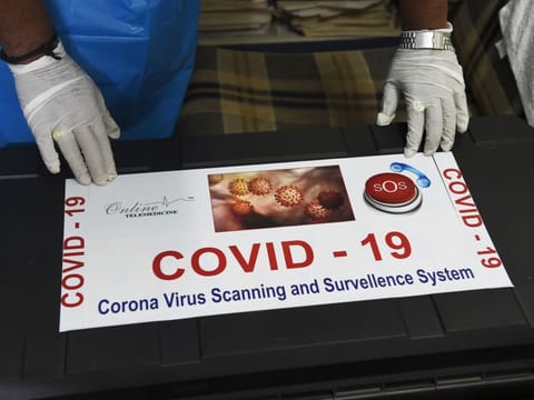 Team member of Ragesh Shah, a scientist and founder of Online Telemedicine Research Institute, puts a sticker on a kit prepared for the coronavirus scanning and surveillance system, in Ahmedabad on March 6. 