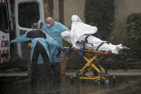(For illustrative purposes only) Medics transport a patient through heavy rain into an ambulance at Life Care Center of Kirkland.