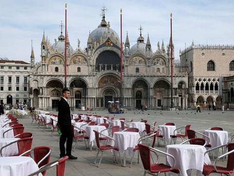 A waiter stands by empty tables outside a restaurant at St Mark's Square after the Italian government imposed a virtual lockdown on the north of Italy including Venice to try to contain a coronavirus outbreak, in Venice, Italy