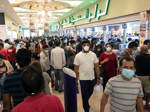 People wearing protective masks, following the coronavirus outbreak, walk at a supermarket in Salmiya, after Kuwait's government announced mandatory work leave for all people in Kuwait