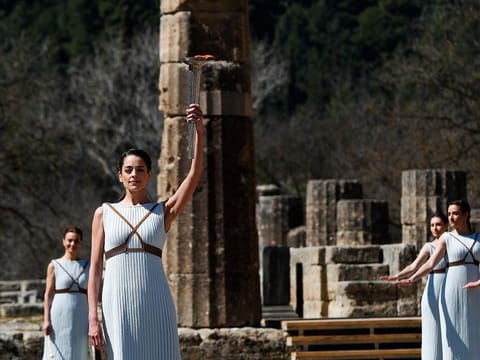Greek actress Xanthi Georgiou, playing the role of the High Priestess, holds up the torch during the flame lighting ceremony at the closed Ancient Olympia site, birthplace of the ancient Olympics in southern Greece