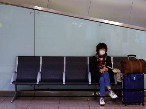 A person wearing a protective mask sits at El Prat airport in Barcelona on March 16, 2020. 