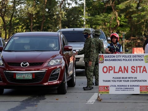 Police stop motorists at a checkpoint in Metro Manila, Philippines on Wednesday, March 18, 2020. 