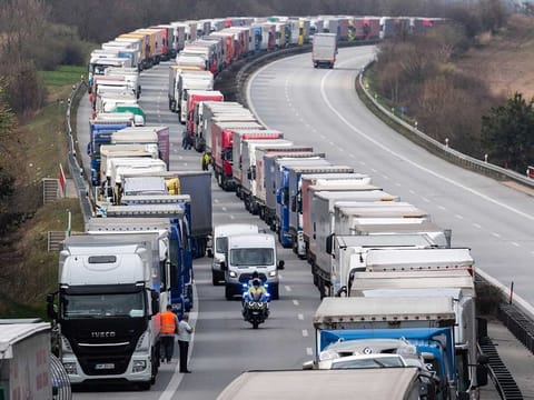 A German police officer drives a  motorcycle between trucks, which jam the motorway A4 near Goerlitz, Germany, on Thursday, March 19, 2020. Thousands of truck drivers have to hold out in a traffic jam, which has grown to a length of about 40 kilometers, before the border with Poland.