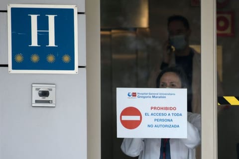 A health worker hangs a placard reading "Restricted entry" on the entrance door of the Gran hotel Colon in Madrid, the first hotel that was transformed into a medical facility to treat the least serious cases amid the outbreak caused by the novel coronavirus, on March 19, 2020.