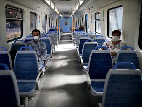 People wearing masks, as a precaution against the spread of the new coronavirus, ride an empty train in Buenos Aires, Argentina.