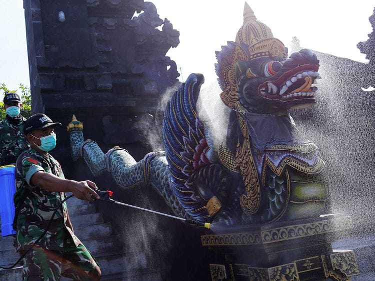 Indonesian soldiers spray disinfectant on a statue to prevent the spread of coronavirus disease (COVID-19) at Tanah Lot temple in Tabanan, Bali, Indonesia, March 20, 2020. 