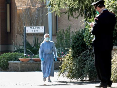 A nun wearing a mask and gloves approaches a Carabinieri officer at the Istituto Figlie di San Camillo (Institute of Daughters of St. Camillo) in Grottaferrata, near Rome, Friday, March 20, 2020. Outbreaks of the coronavirus have stricken two convents in the Rome area.