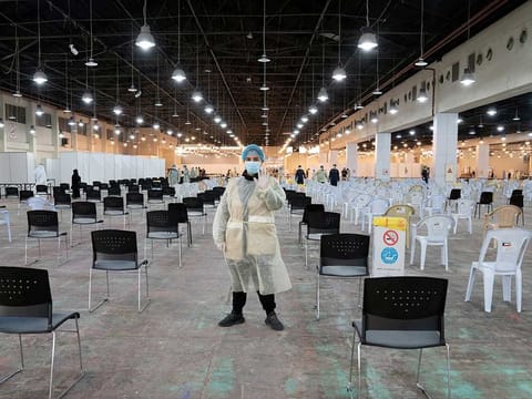 A volunteer who directs visitors at a coronavirus testing centre, gestures at the Kuwait International Fairgrounds in Mishref, Kuwait on March 18.