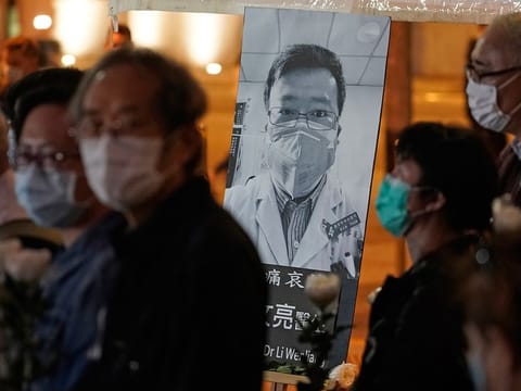In this Feb. 7, 2020, file photo, people wearing masks attend a vigil for Chinese doctor Li Wenliang, who was reprimanded for warning about the outbreak of the new coronavirus, in Hong Kong. 