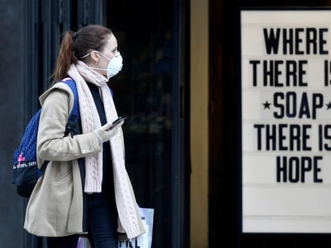 A woman wearing a protective face mask walks past a shop, as the spread of the coronavirus disease (COVID-19) continues, in London on March 20, 2020.