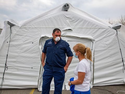 Medical personal stand near a tent in a field hospital, run by non-governmental organisation Samaritans Purse, in a parking lot in Cremona, Italy, on Friday, March 20, 2020.