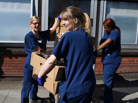 Nurses and staff carry food delivered by volunteers outside Guy's and St Thomas' Hospital as the spread of the coronavirus disease (COVID-19) continues, in London on March 23, 2020.