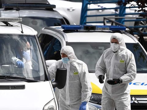 Members of the Spanish Army's Military Emergency Unit (UME) wearing protective suits talk to undertakers driving a van outside the the Palacio de Hielo (Ice Palace) shopping mall where an ice rink was turned into a temporary morgue on March 24, 2020 in Madrid to deal with a surge in deaths in the Spanish capital due to the coronavirus.