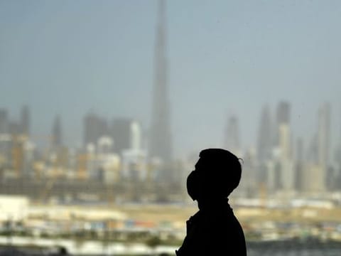 File image: A man wearing a protective mask stands at a racetrack overlooking Dubai 