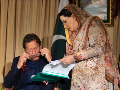 Pakistan government spokesperson Firdous Ashiq Awan consults with Pakistani Prime Minister Imran Khan in Islamabad, Pakistan, Monday, March 16, 2020. Khan said Monday he fears the new coronavirus will devastate developing nations' economies, and warned richer economies to prepare to write off the debts of the world's poorer countries. 