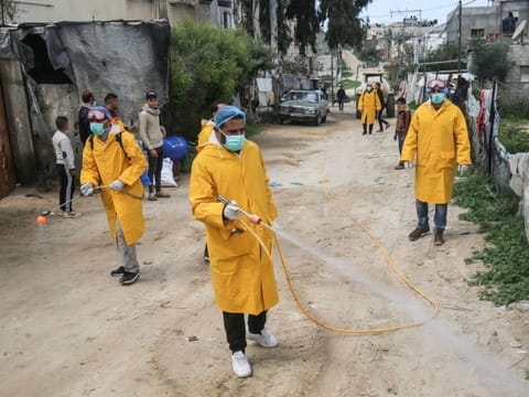 Palestinian volunteers wearing protective clothes and masks  disinfect a street as a preventive measure against the spread of novel coronavirus, in Rafah in the southern Gaza Strip, on March 22, 2020.  Authorities in Gaza today confirmed the first two cases of novel coronavirus, identifying them as Palestinians who had travelled to Pakistan and were being held in quarantine since their return. 
The United Nations has warned that a COVID-19 outbreak in Gaza could be disastrous, given the high poverty rates and weak health system in the coastal strip under Israeli blockade since 2007.  / AFP / SAID KHATIB