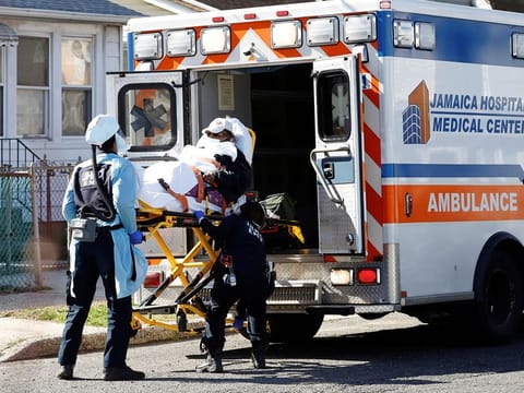 Emergency Medical Technicians (EMT) lift a patient into an ambulance while wearing protective gear, as the outbreak of coronavirus disease (COVID-19) continues, in New York City.