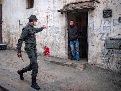 A member of Morocco's Interior Ministry Auxiliary Forces, patrolling as part of a larger combined security force, instructs a man to remain at home as a measure against the COVID-19 coronavirus pandemic in the capital Rabat's district of Takadoum on March 27, 2020
