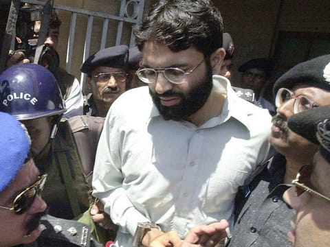 Pakistani police surround handcuffed Omar Sheikh as he comes out of a court in Pakistan's port city of Karachi on March 29, 2002. A Pakistani court on April 2, 2020 overturned the death sentence for British-born militant Ahmed Omar Saeed Sheikh, who had been convicted over the 2002 killing of American journalist Daniel Pearl. But on Friday, Pakistan authorities ordered that the men be detained for three more months.
