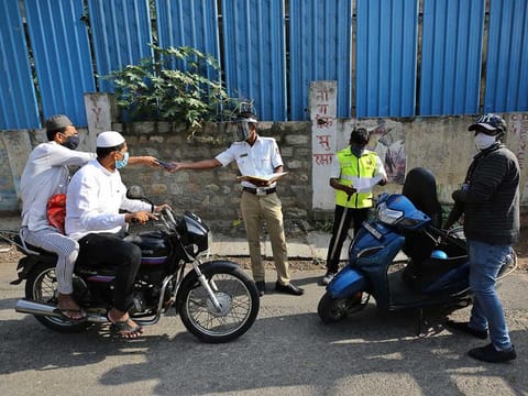 An Indian policeman checks the identity of motorists before allowing them to proceed at a checkpoint during lockdown in Bangalore, India, Friday, April 10, 2020.