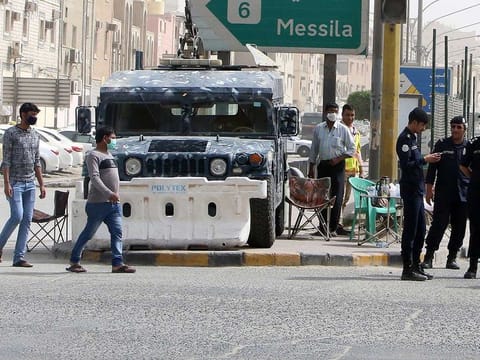 Kuwaiti police officers man a checkpoint at the entrance the town of Jeleeb Al-Shuyoukh, south the capital Kuwait City after the district was put on lockdown. 
