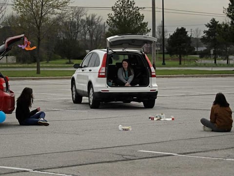 Friends Paige Snider, Maeve MacNaughton, and Maya Wood gather while keeping their distance to celebrate Snider's belated birthday in a high school parking lot on April 10, 2020, in Olathe, Kansas, US. 