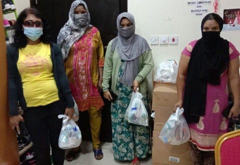 Foreign residents in Bahrain carry charity food parcels distributed as part of a public relief initiative. 
