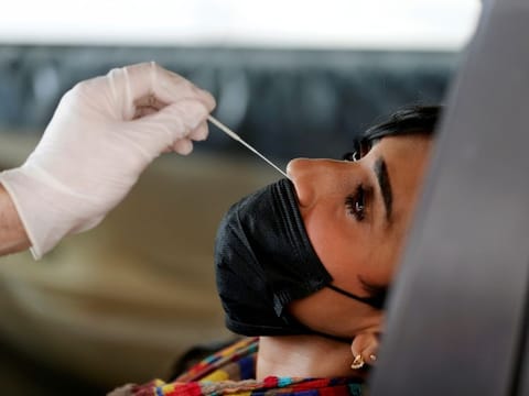 A member of medical staff wearing protective gloves takes a swab from a woman during drive-thru coronavirus testing at Bahrain Exhibition Centre, in Manama April 9.